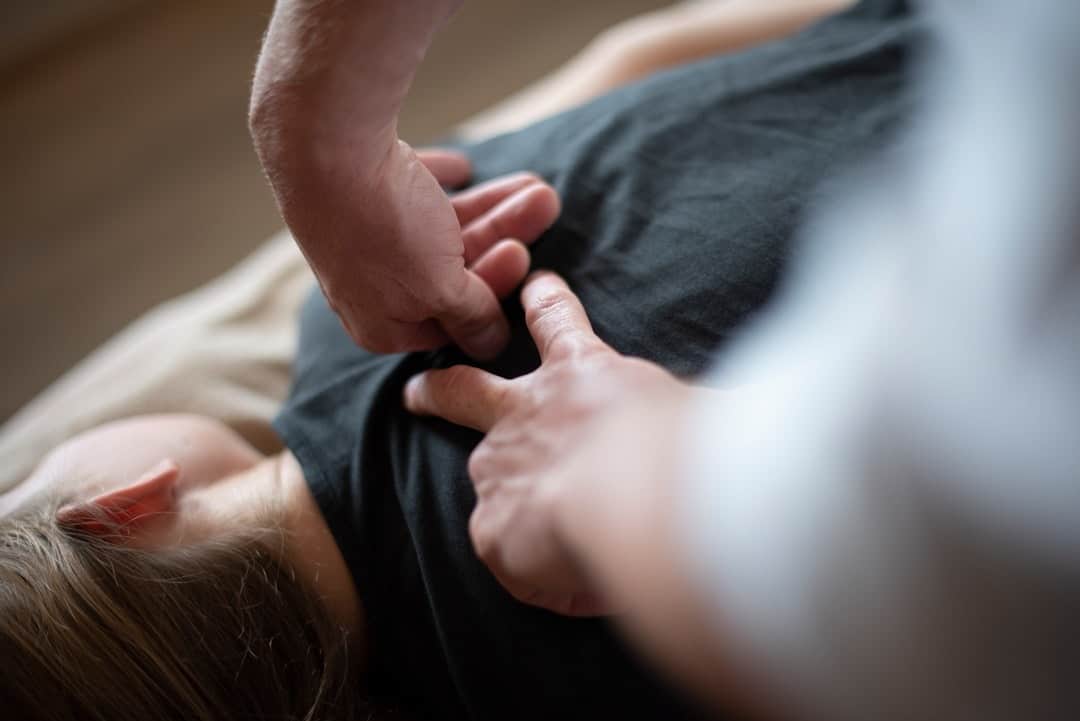 Hands performing a therapeutic adjustment on a person's upper back.